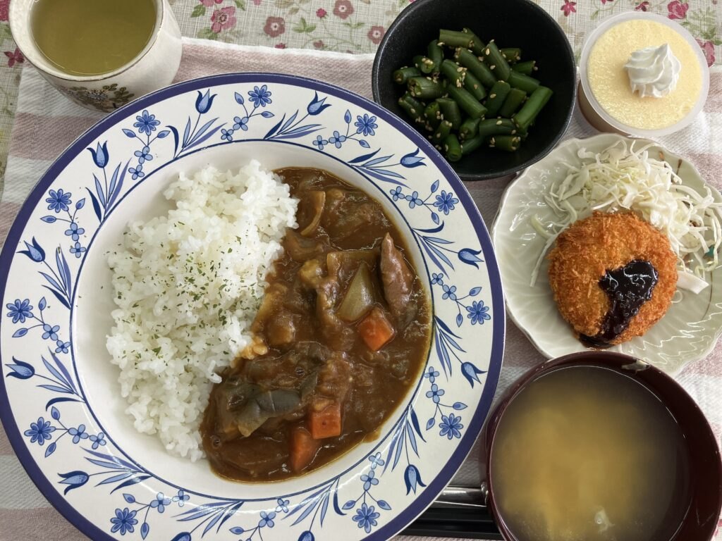 今日のお昼ごはん。ピリ辛カレーライスにいんげんの胡麻和え、コロッケ添え