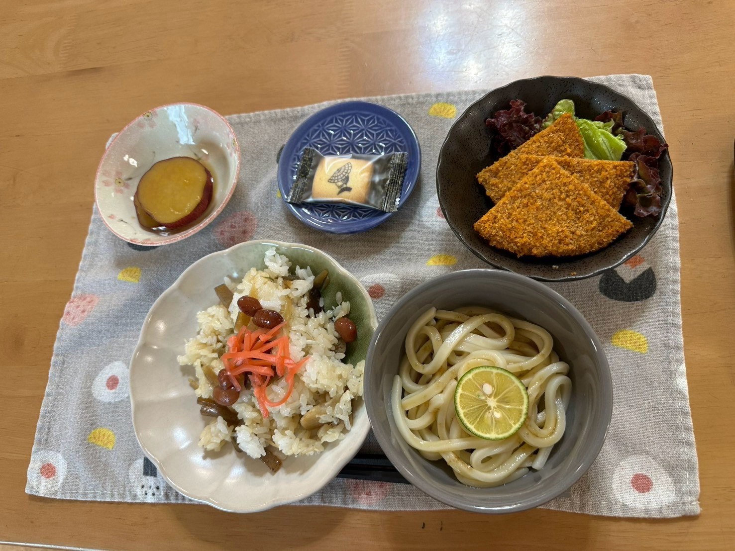 混ぜご飯、冷たいうどん、揚げ物、さつまいもが並ぶ8月12日のお昼ご飯