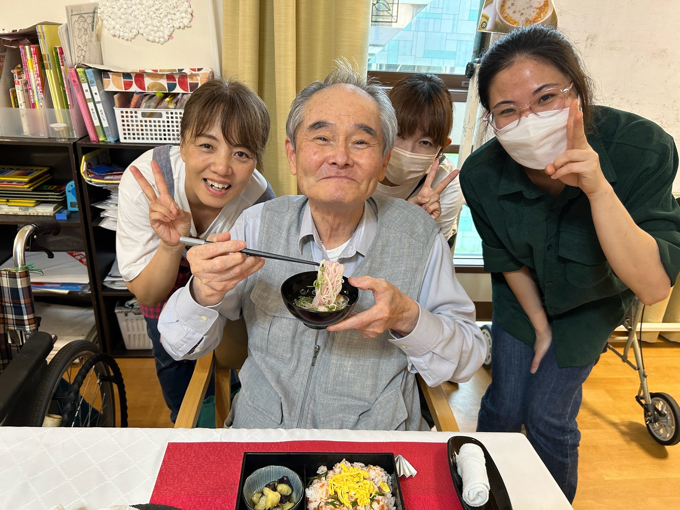 麺のお椀を手にする利用者さんを職員が囲む様子