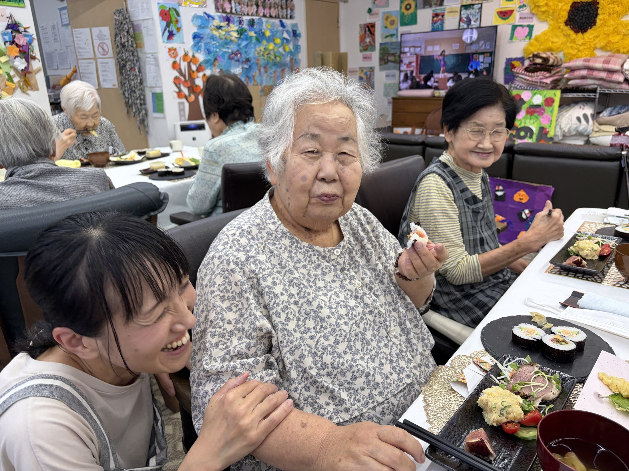 巻き寿司を手に食事を楽しむ白山の利用者さんと職員