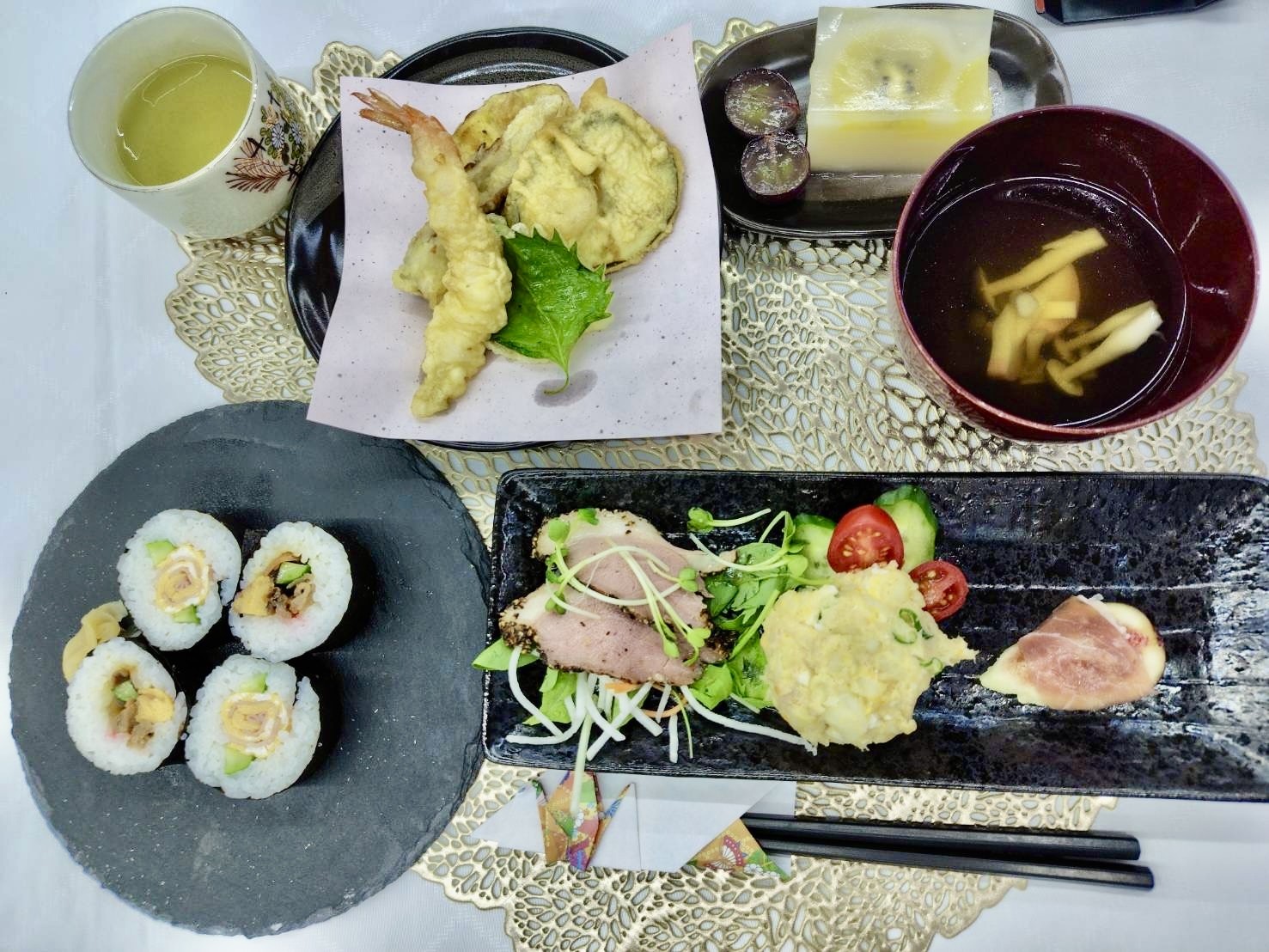 巻き寿司、天ぷら、サラダ、お吸い物、デザートが並ぶ白山のお祝いの食事