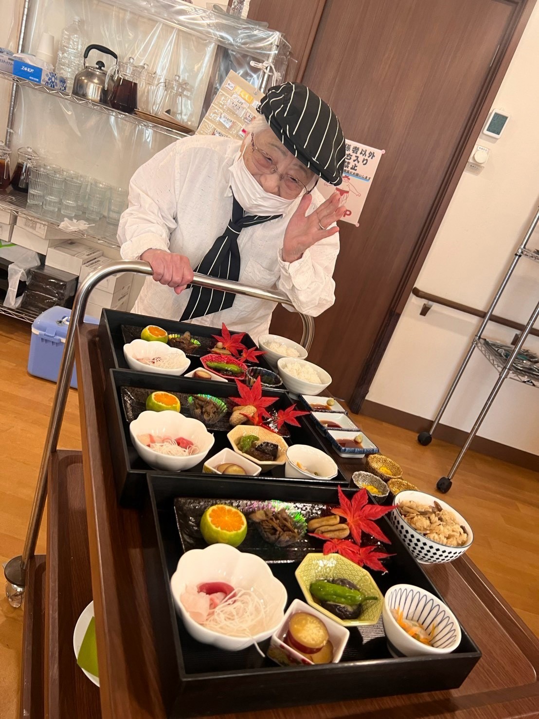 料理を載せたワゴンのそばで手を振るカフェの装いの方