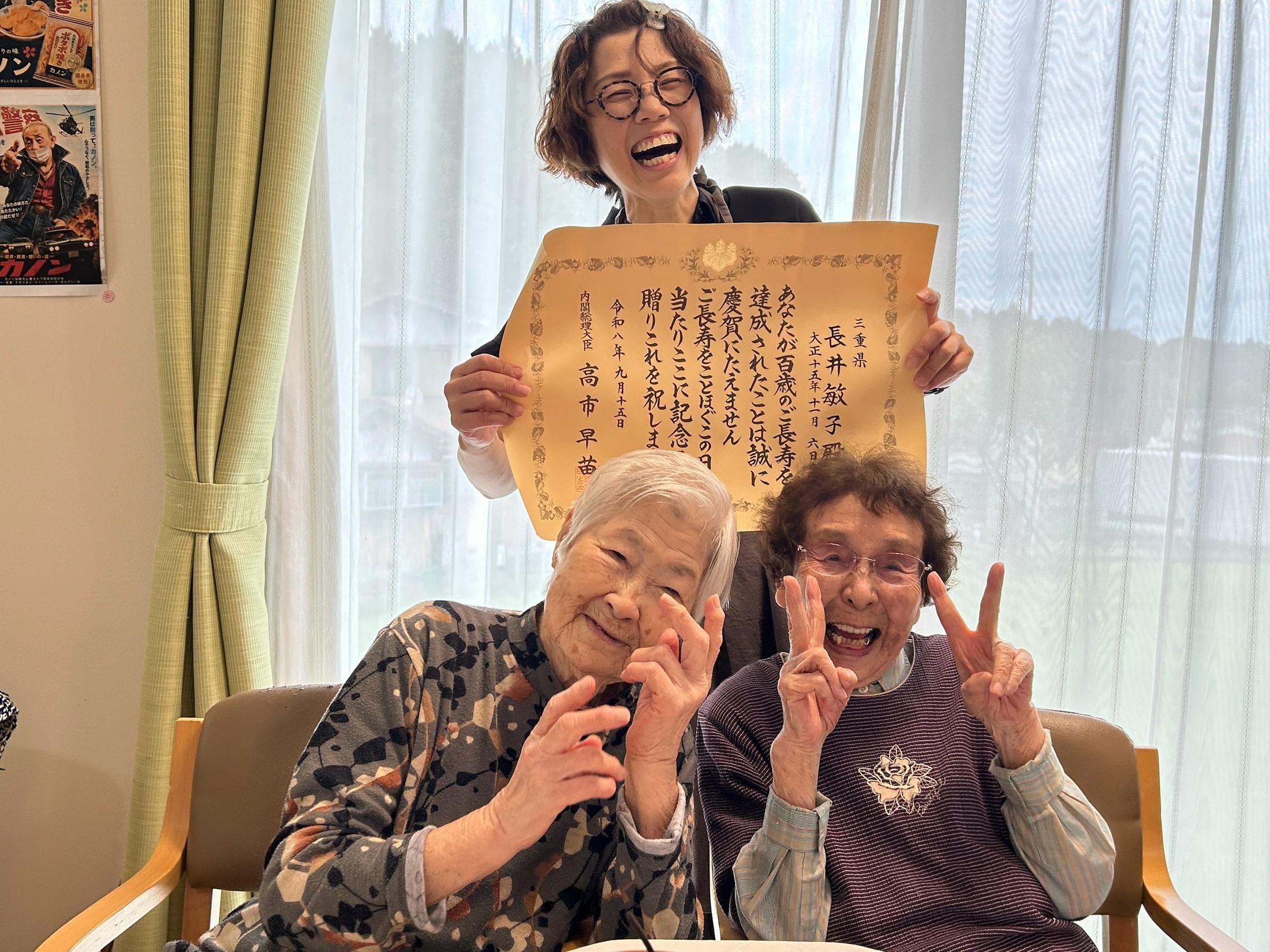 百歳のお祝いの賞状を囲んで笑顔で記念撮影する皆さん
