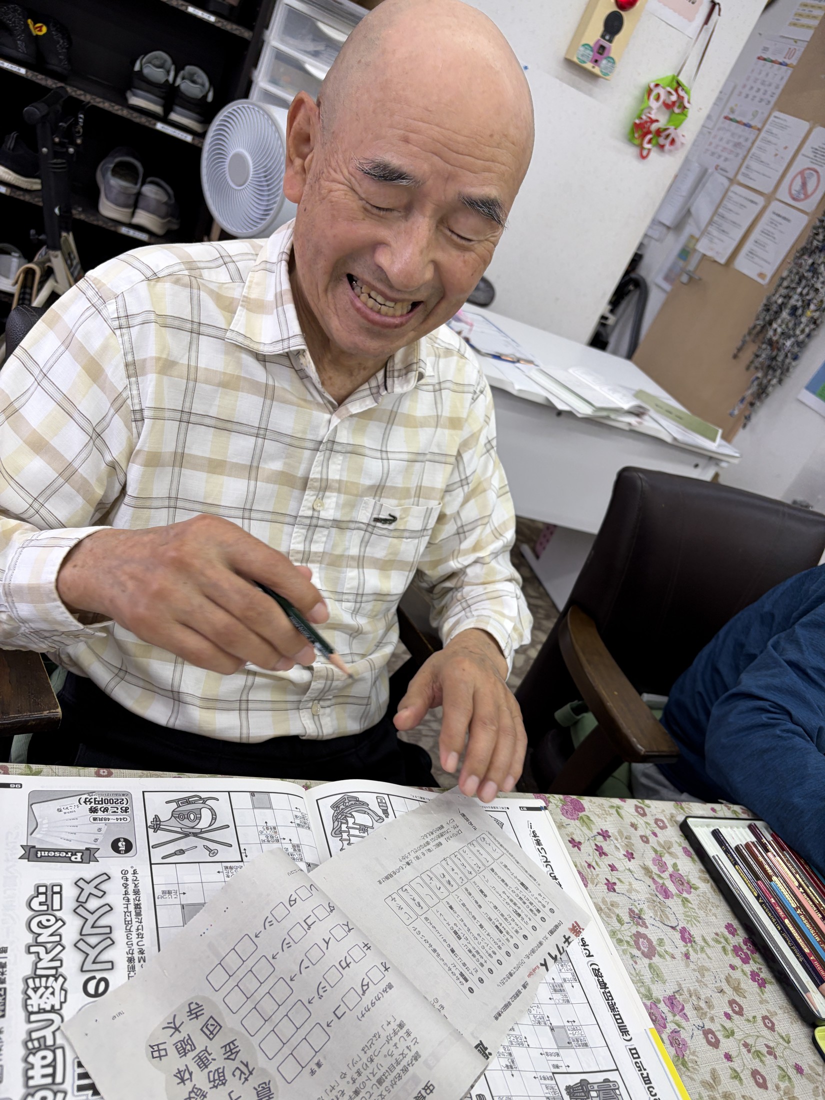 鉛筆を手にプリントに取り組みながら笑顔を見せる利用者さん