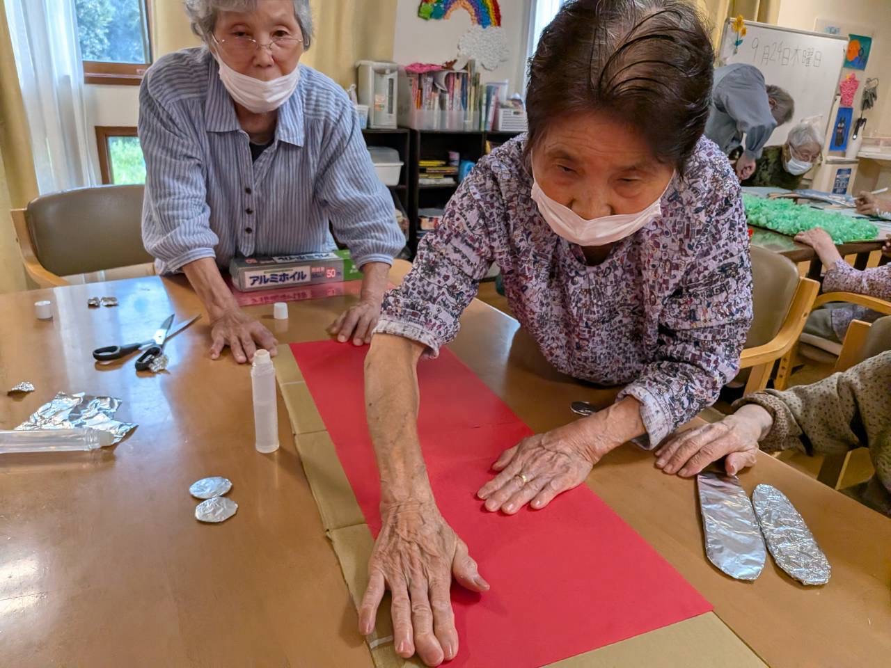 赤い紙とアルミホイルの部品を前に文化祭の制作を進める皆さん