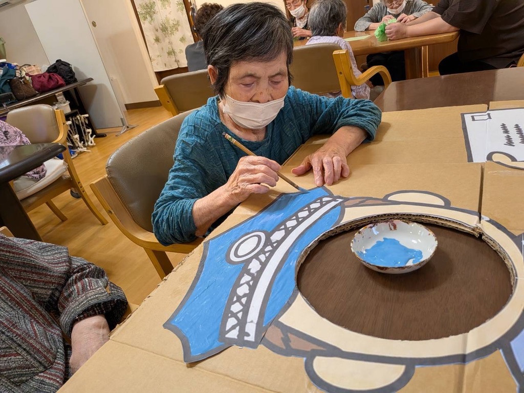 看板に青い絵の具を塗る利用者さん