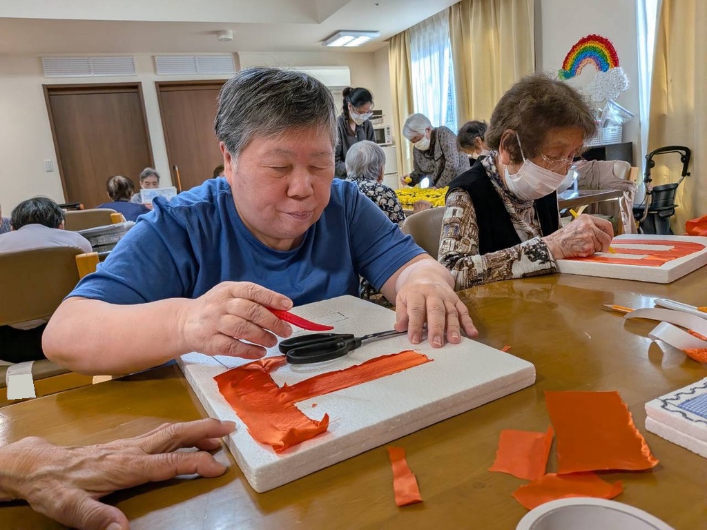 オレンジ色の布できめこみパッチワークを進める利用者さん