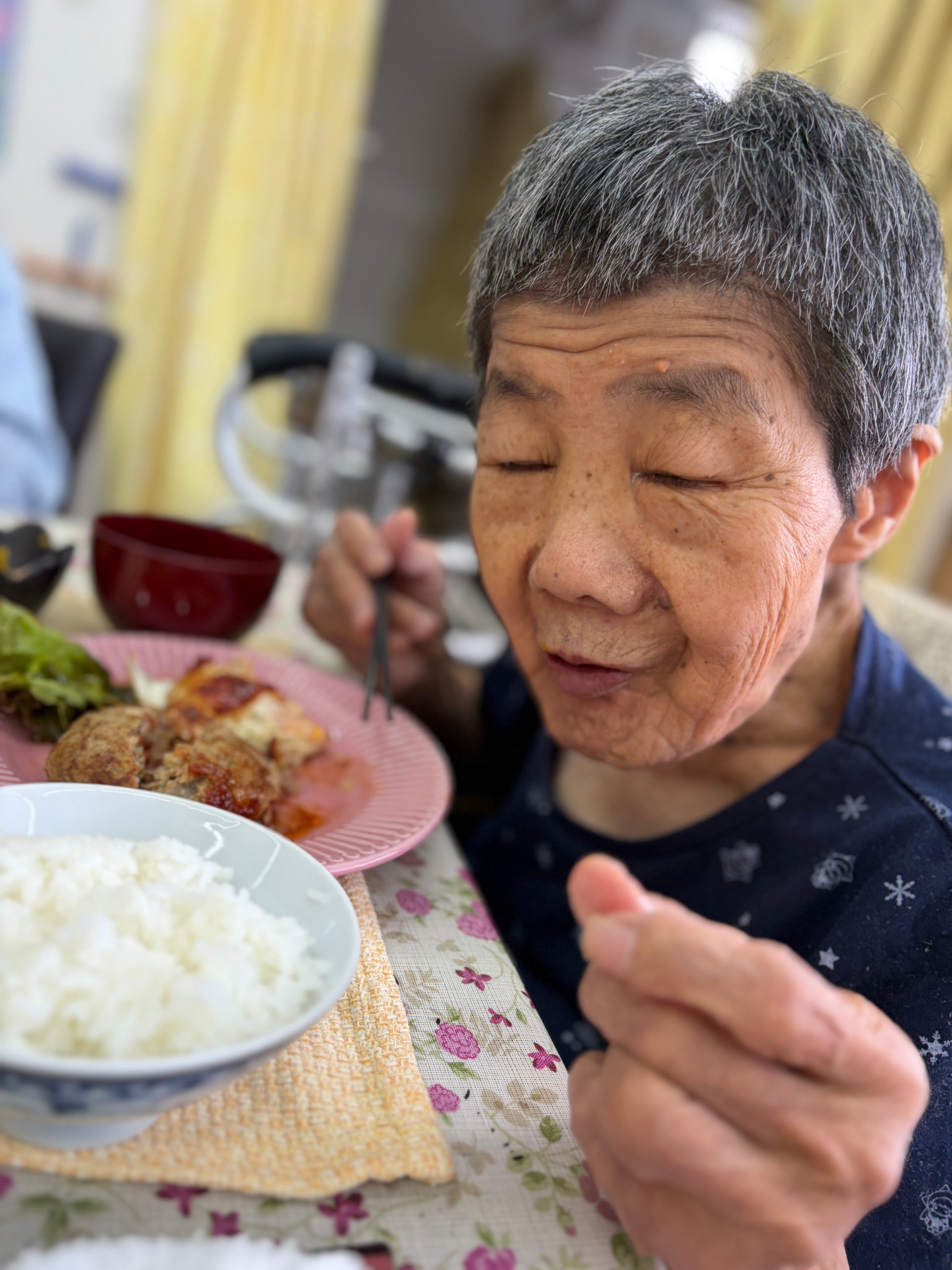 ハンバーグの食事を前に箸を手にする利用者さん