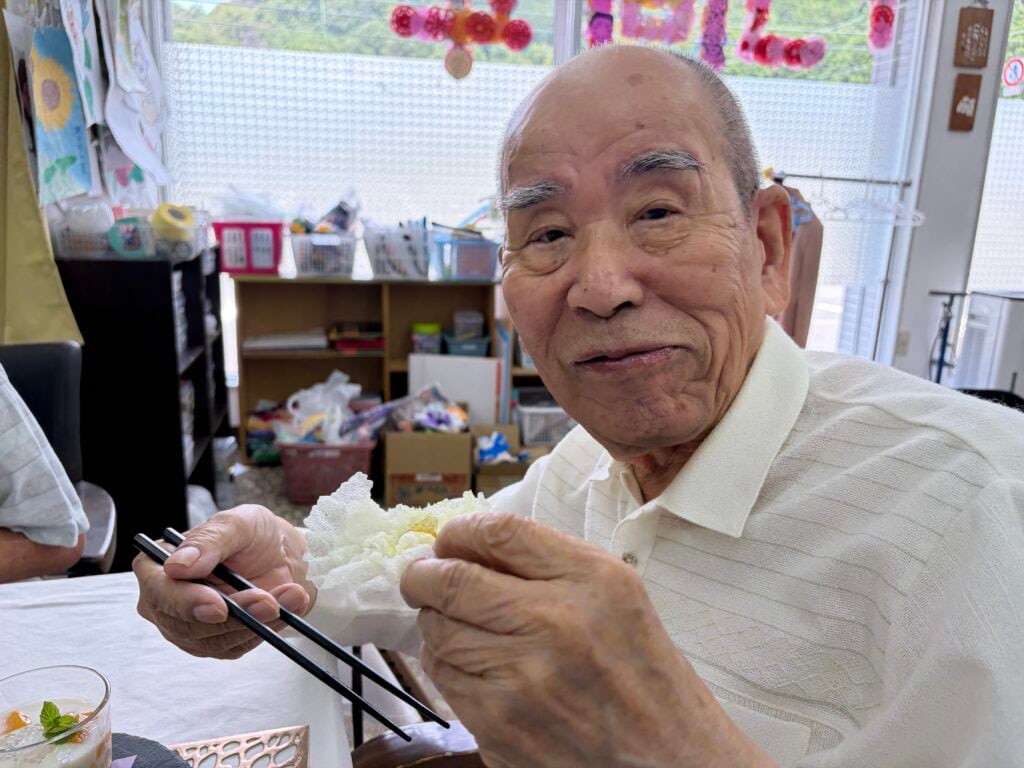 生春巻きの皮で作ったお花の飾りを手に取る男性のご利用者様